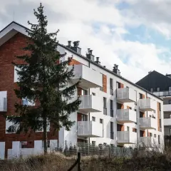 Nowoczesne bloki mieszkalne z balkonami, idealne na dom na raty notarialne. W tle sosna i błękitne niebo.