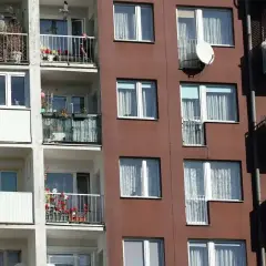 Blok mieszkalny z balkonami, na których widać rośliny i antenę satelitarną. Czy mieszkanie TBS można wykupić?