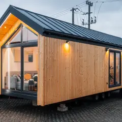 Nowoczesne domy z kontenerów, projekty i ceny. Drewniana elewacja, duże okna i oświetlenie tworzą przytulną atmosferę.