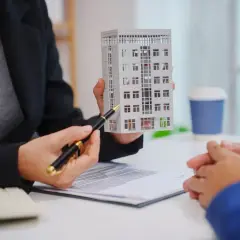 Doradca nieruchomości prezentuje makietę budynku, omawiając ceny mieszkań w Katowicach.
