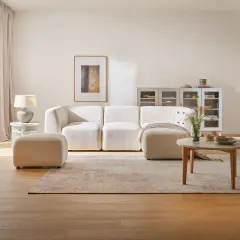 Przytulny salon z kanapą i pufą w odcieniach beżu. Beżowy kolor ścian tworzy ciepłą atmosferę.