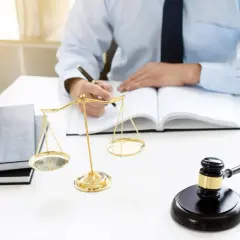 Prawnik analizuje, kto dziedziczy mieszkanie nabyte przed ślubem. Waga sprawiedliwości i młotek sędziego symbolizują prawo.