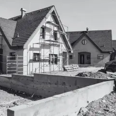 Domy w budowie, rusztowania, koparka i betonowe fundamenty. Wkrótce będzie pozwolenie na budowę i nowe domy.