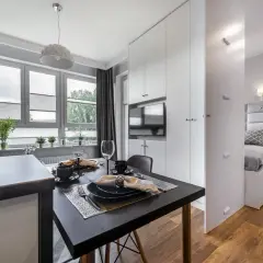 Stylowa garsoniera z aneksem kuchennym, jadalnią i wydzieloną sypialnią. Eleganckie meble i detale tworzą przytulną atmosferę.
