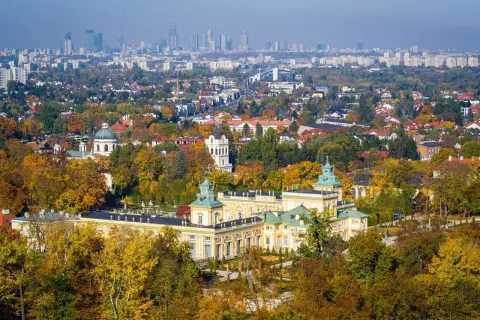 Pałac wilanowski otoczony jesiennym parkiem, z panoramą Warszawy w tle. To symbol najbogatszej dzielnicy Warszawy.