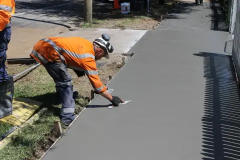 Robotnik wygładza świeży beton. Sprawdź, jaka jest kubik betonu cena, by zaplanować budowę!