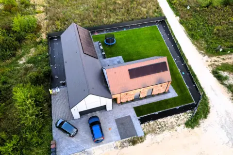 Nowy dom z panelami słonecznymi, zielonym trawnikiem i trampoliną. Planujesz budowę w 2026? Sprawdź, jak może wyglądać Twój przyszły dom.