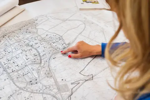 Kobieta analizuje szczegółowy plan zagospodarowania przestrzennego, wskazując palcem konkretny obszar na mapie.