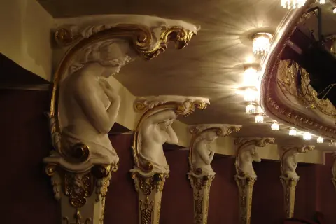 Rząd białych, zdobionych złotem kariatyda wspiera sufit teatru.