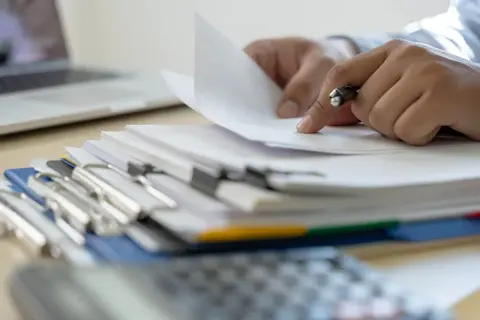 Ręce przeglądają dokumenty, szukając informacji, kiedy można wymeldować członka rodziny.