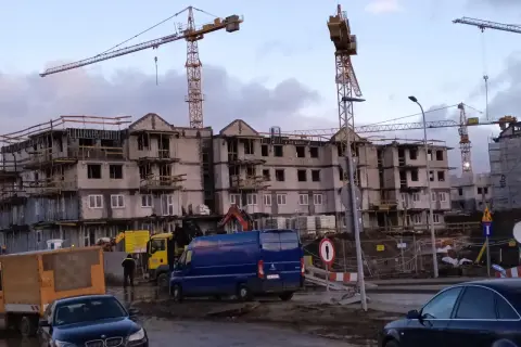 Budowa bloków mieszkalnych w Gdańsku. W tle dźwigi budowlane, na pierwszym planie samochody i maszyny budowlane. Ceny mieszkań gdańsk mogą być wysokie.