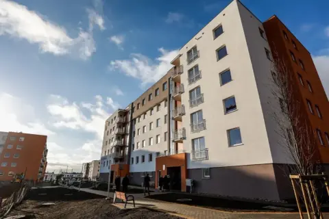 Nowe bloki mieszkalne, jeden z pomarańczową elewacją. Zastanawiasz się, co to znaczy, gdy ktoś chce odstąpić mieszkanie TBS?