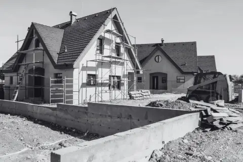 Domy w budowie, rusztowania, koparka i betonowe fundamenty. Wkrótce będzie pozwolenie na budowę i nowe domy.