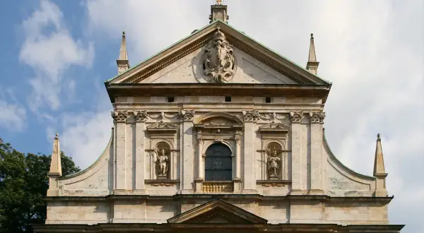 Majestatyczna fasada kościoła, przykład bogatej architektury baroku, z rzeźbami i zdobieniami.