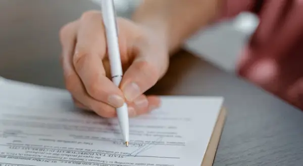 Dłoń podpisuje aneks do umowy najmu okazjonalnego. Dokument zawiera pola dotyczące danych podatkowych i działalności gospodarczej.