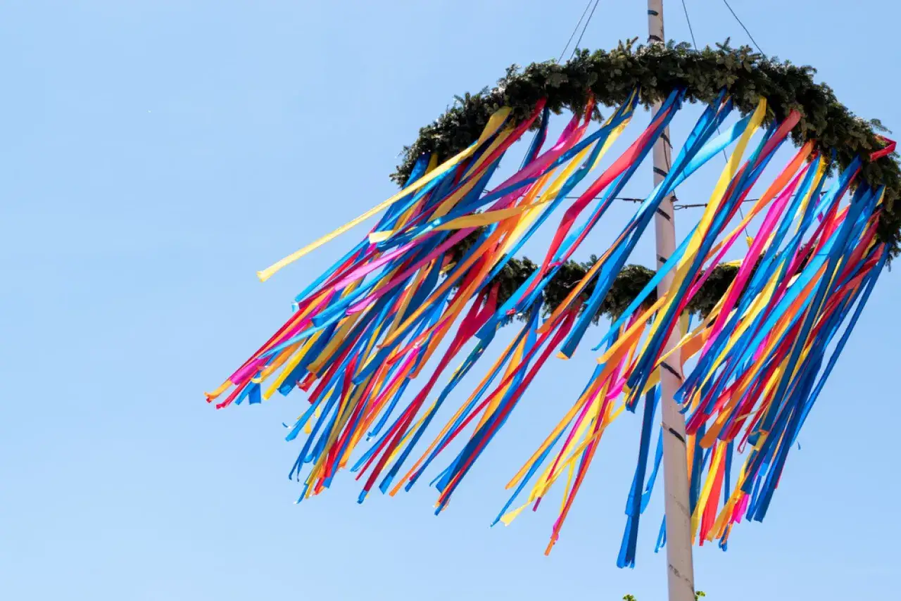 Kolorowa wiecha z wstążkami powiewa na tle błękitnego nieba, symbolizując radość i świętowanie.