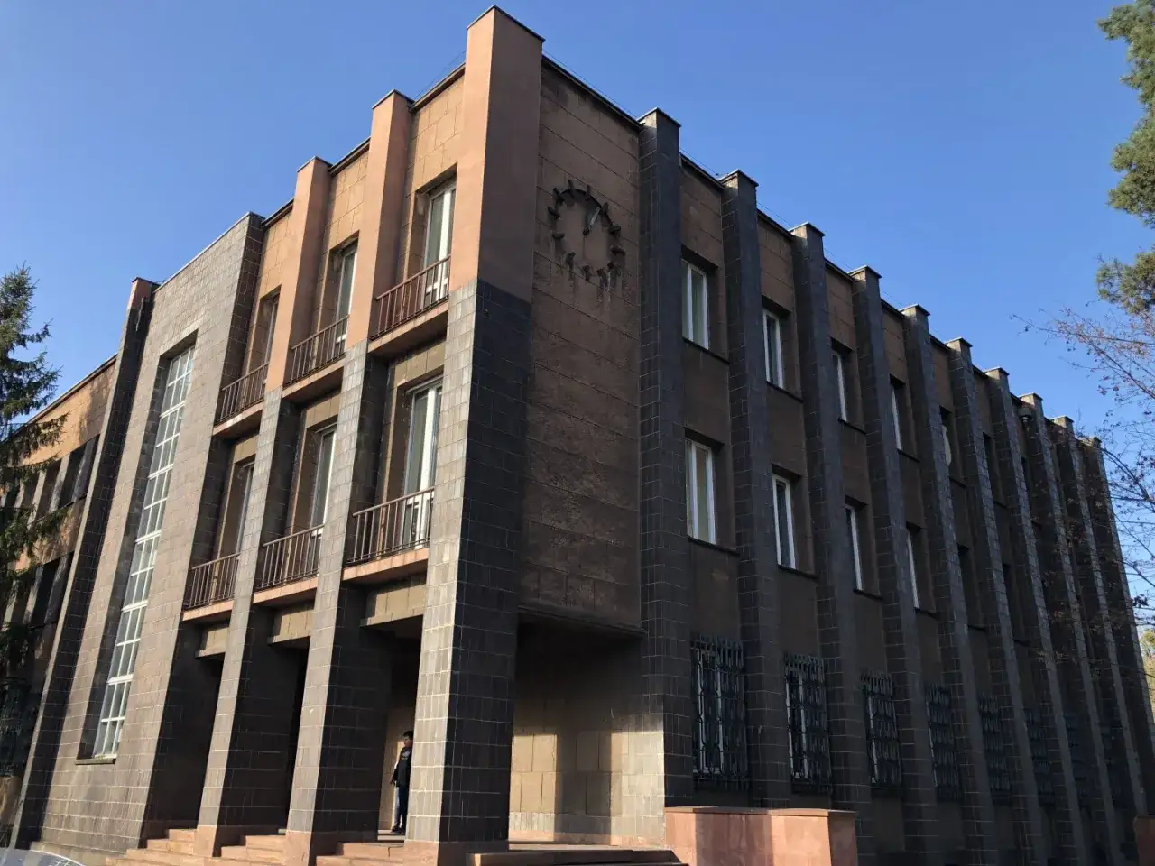 Budynek w stylu art deco z charakterystycznymi pionowymi elementami i zegarem na fasadzie.