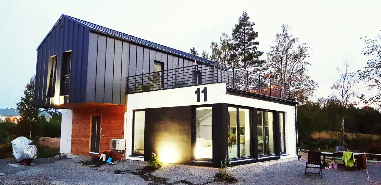Nowoczesny dom z kontenerów 100m2 cena. Elegancka bryła z drewnianymi i metalowymi elementami, taras z oświetleniem.