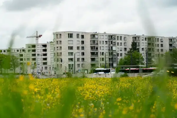Bloki mieszkalne w budowie, z dźwigiem w tle. Obok droga z autobusami. Zastanawiasz się, ile zarabia deweloper na bloku?