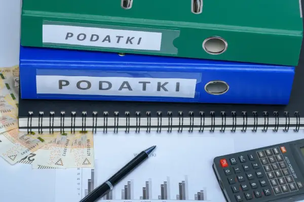 Dwa segregator "PODATKI", zeszyt, pieniądze i kalkulator. Jak zmniejszyć podatek za budynki gospodarcze?
