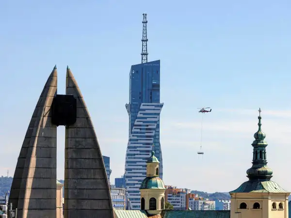 Widok na najwyższy budynek mieszkalny w Polsce, z helikopterem dostarczającym ładunek.