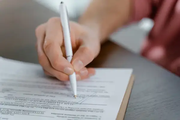 Dłoń podpisuje aneks do umowy najmu okazjonalnego. Dokument zawiera pola dotyczące danych podatkowych i działalności gospodarczej.