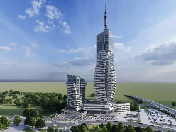Nowoczesne wieżowce w Rzeszowie, w tym rzeszów najwyższy budynek, z charakterystyczną, skręconą fasadą i anteną na szczycie. Otoczone zielenią i parkingiem.