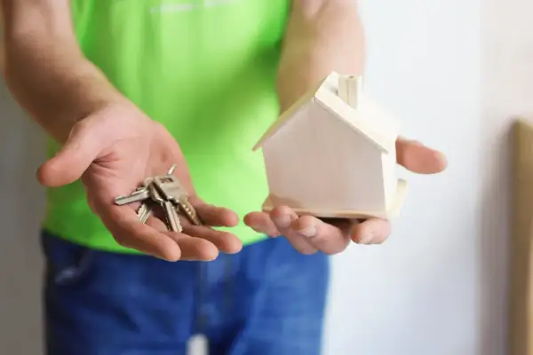 Ręce trzymają klucze i model domu. Zastanawiasz się, na co zwrócić uwagę przy umowie najmu?
